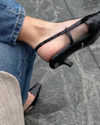 Woman wearing black slingback heels with legs crossed.