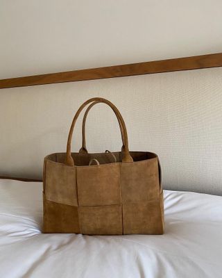 A quiet luxury handbag from Bottega Veneta sitting on a white sheet.