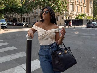 Woman wearing an off-the-shoulder top and jeans.