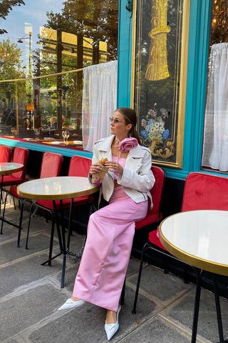 a woman's skirt outfit with a pink satin maxi skirt with a matching bandeau top and a white moto jacket and white pumps