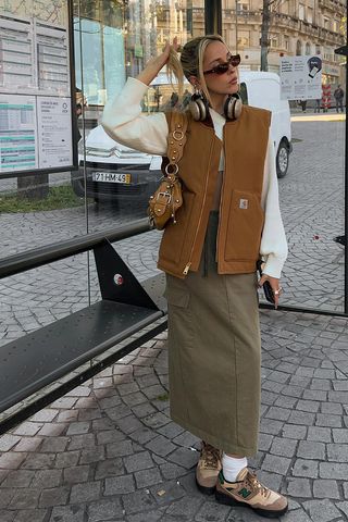 a woman's skirt outfit with a cargo skirt and sweatshirt and utility vest and sneakers