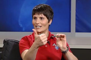 International Space Station Expedition 42 flight engineer Samantha Cristoforetti holds out her thumb, mimicking the hand on her “Don't Panic” patch, inspired by "The Hitchhiker's Guide to the Galaxy."