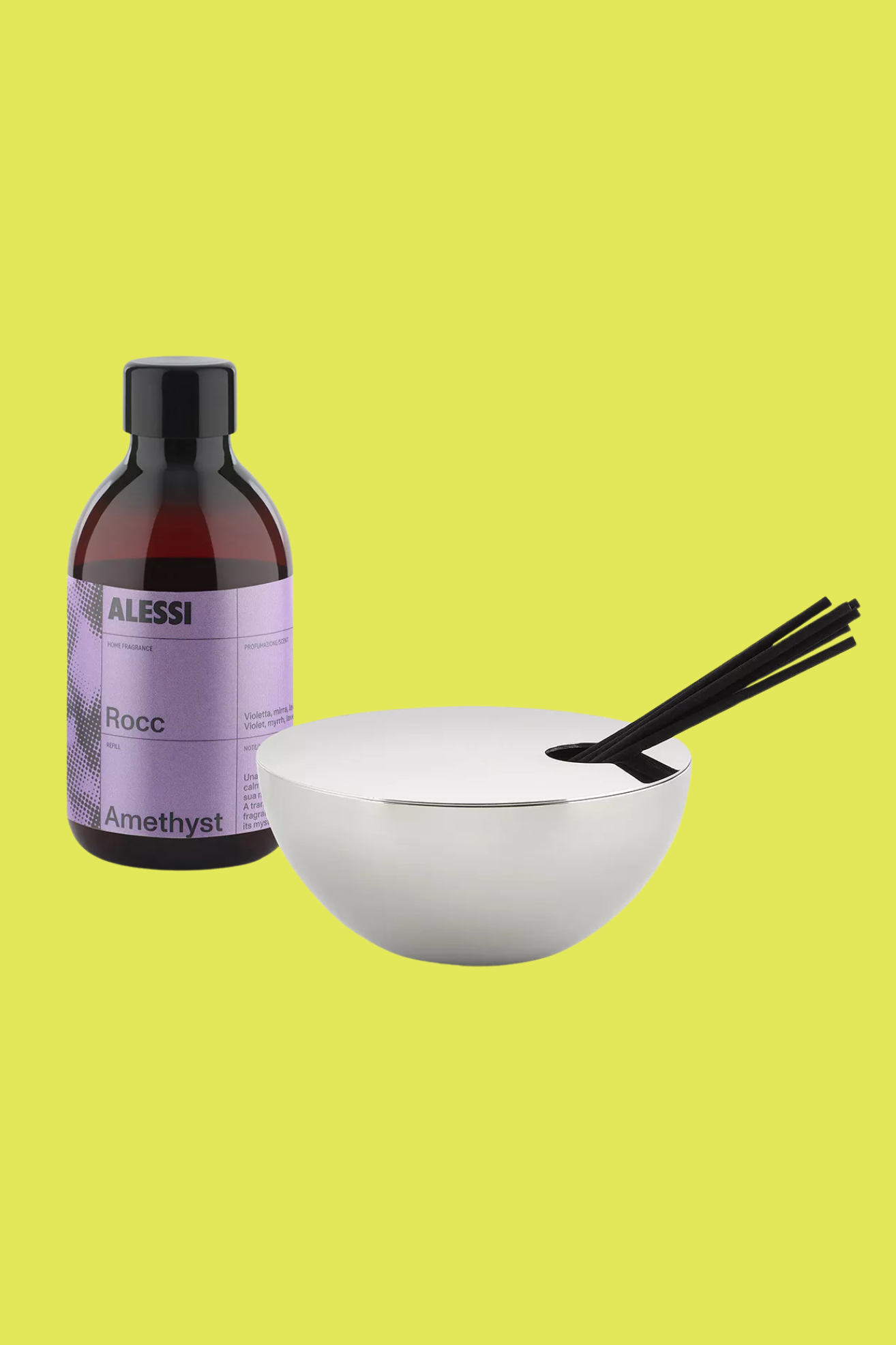 A chrome bowl reed diffuser with black reeds by a bottle of fragrance oil