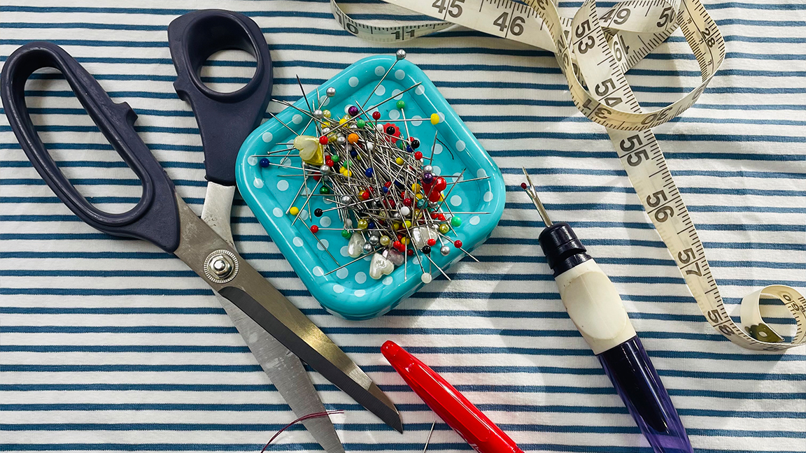 How to start sewing; a mix of scissors and pins on a piece of striped fabric