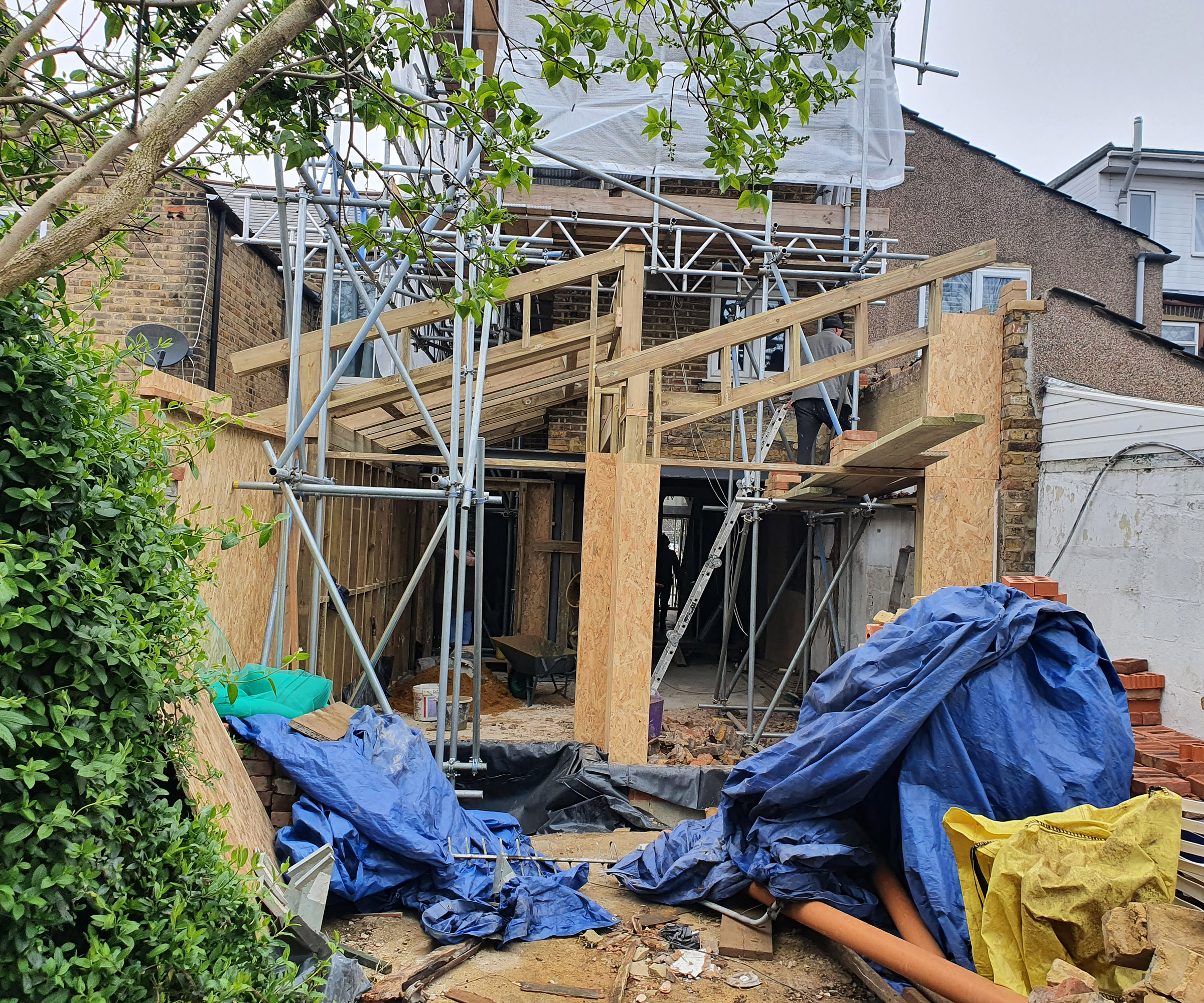 Construction of a saw-tooth roof kitchen extension in progress with lots of builders mess and scaffolding