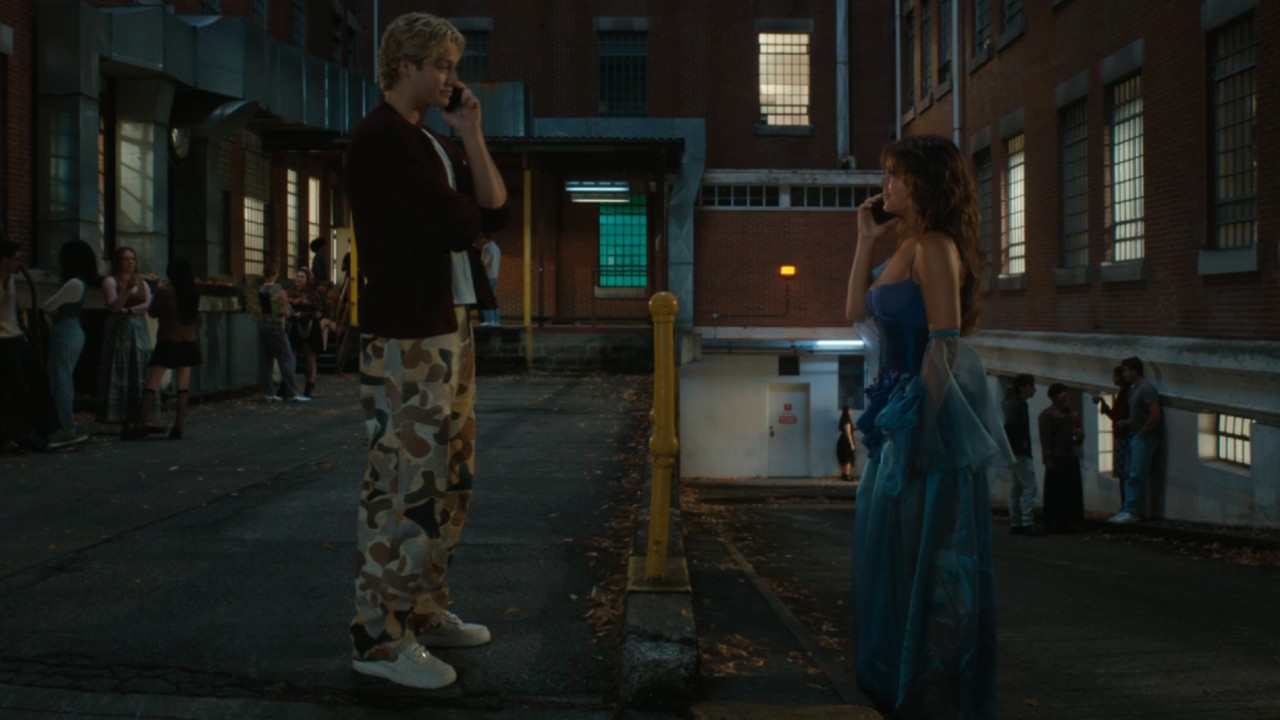 From left to right: Dean standing with his phone to his ear facing Allie who is facing him and holding a phone to her ear.