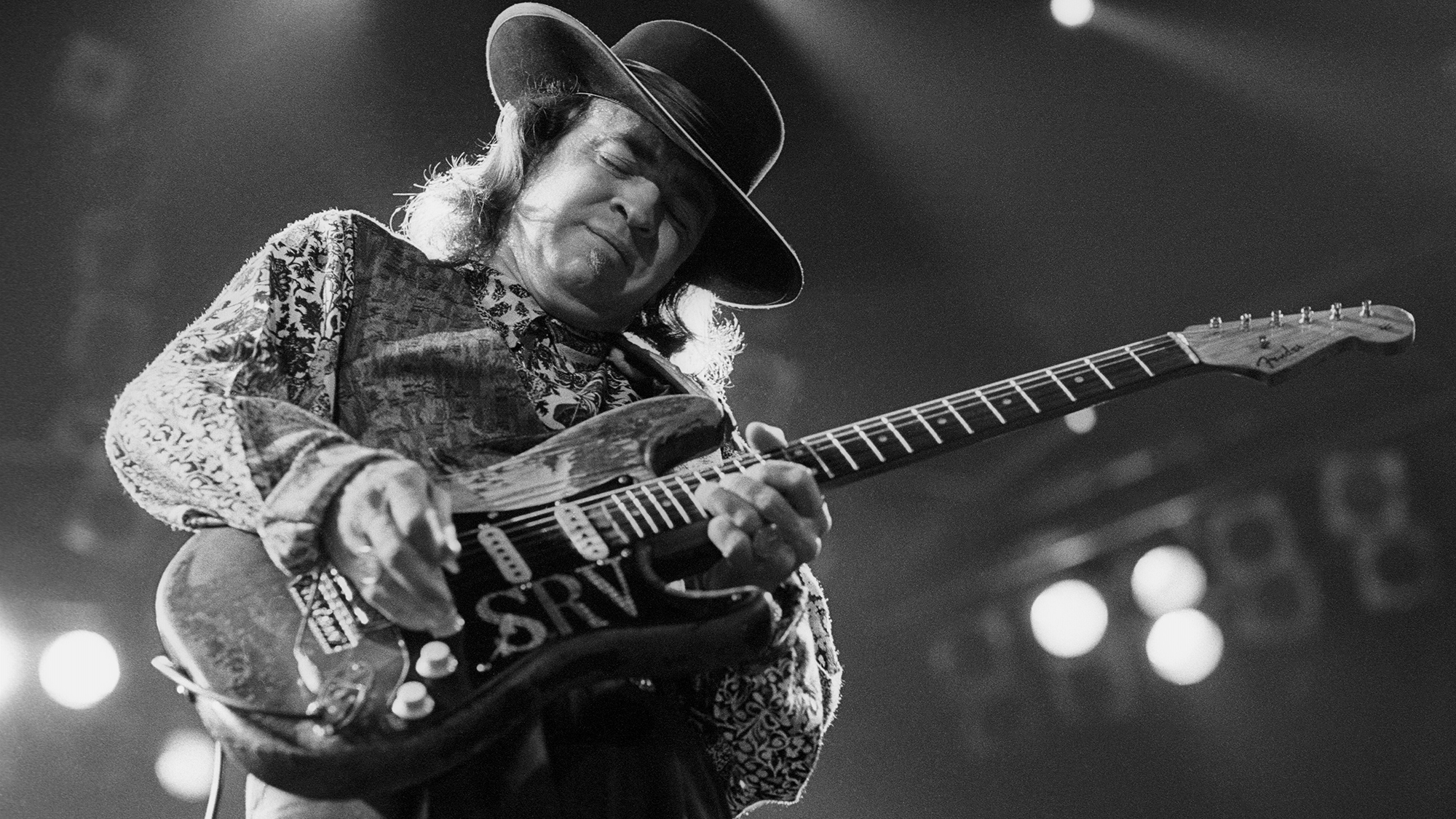 Stevie Ray Vaughan performing at the Oakland Coliseum Arena on December 3, 1989. He plays a Fender Stratocaster guitar.