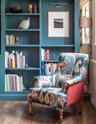 Blue living room with painted bespoke shelving and patterned armchair