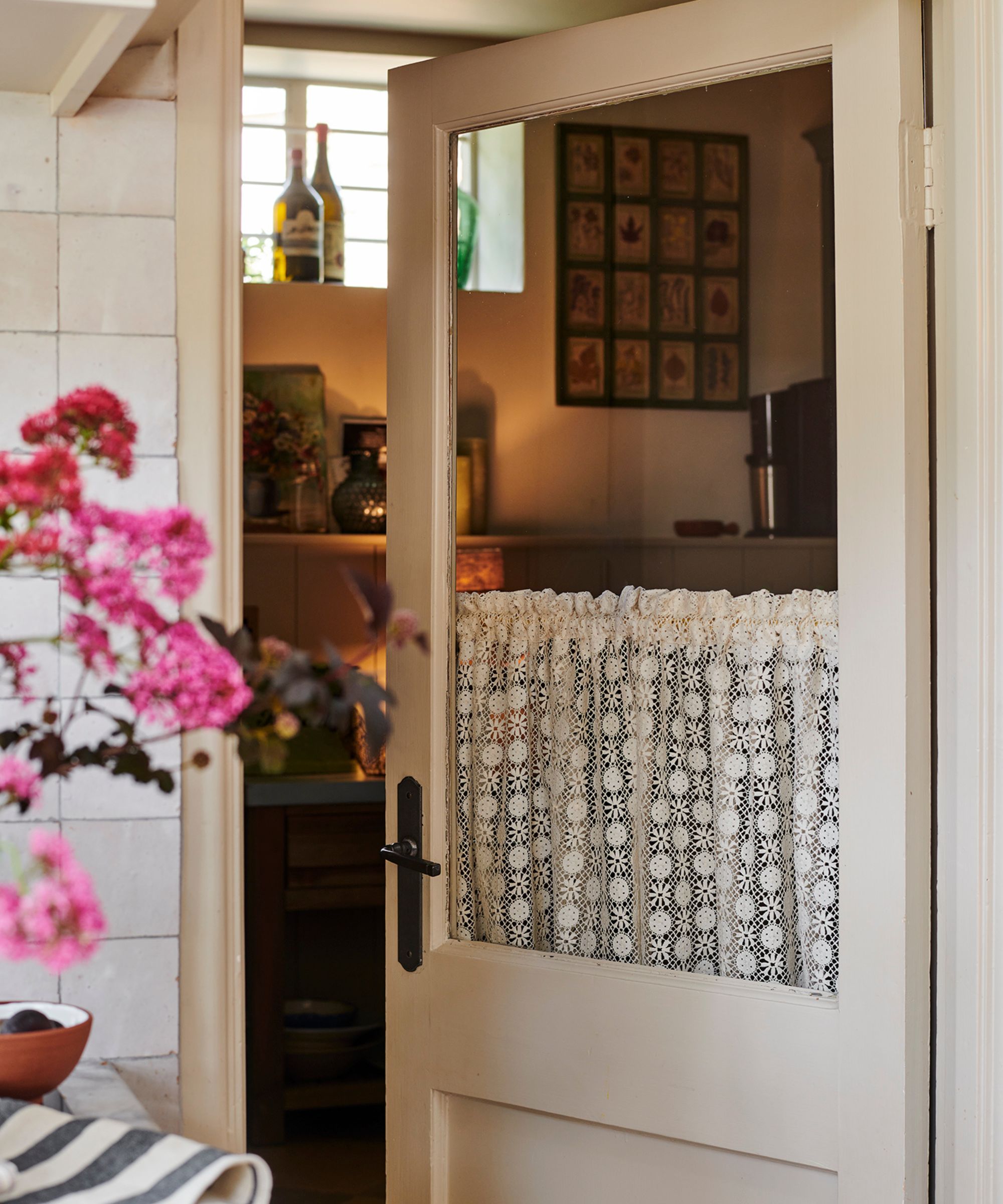 Back door painted white with a lace cafe curtain, looking into a kitchen