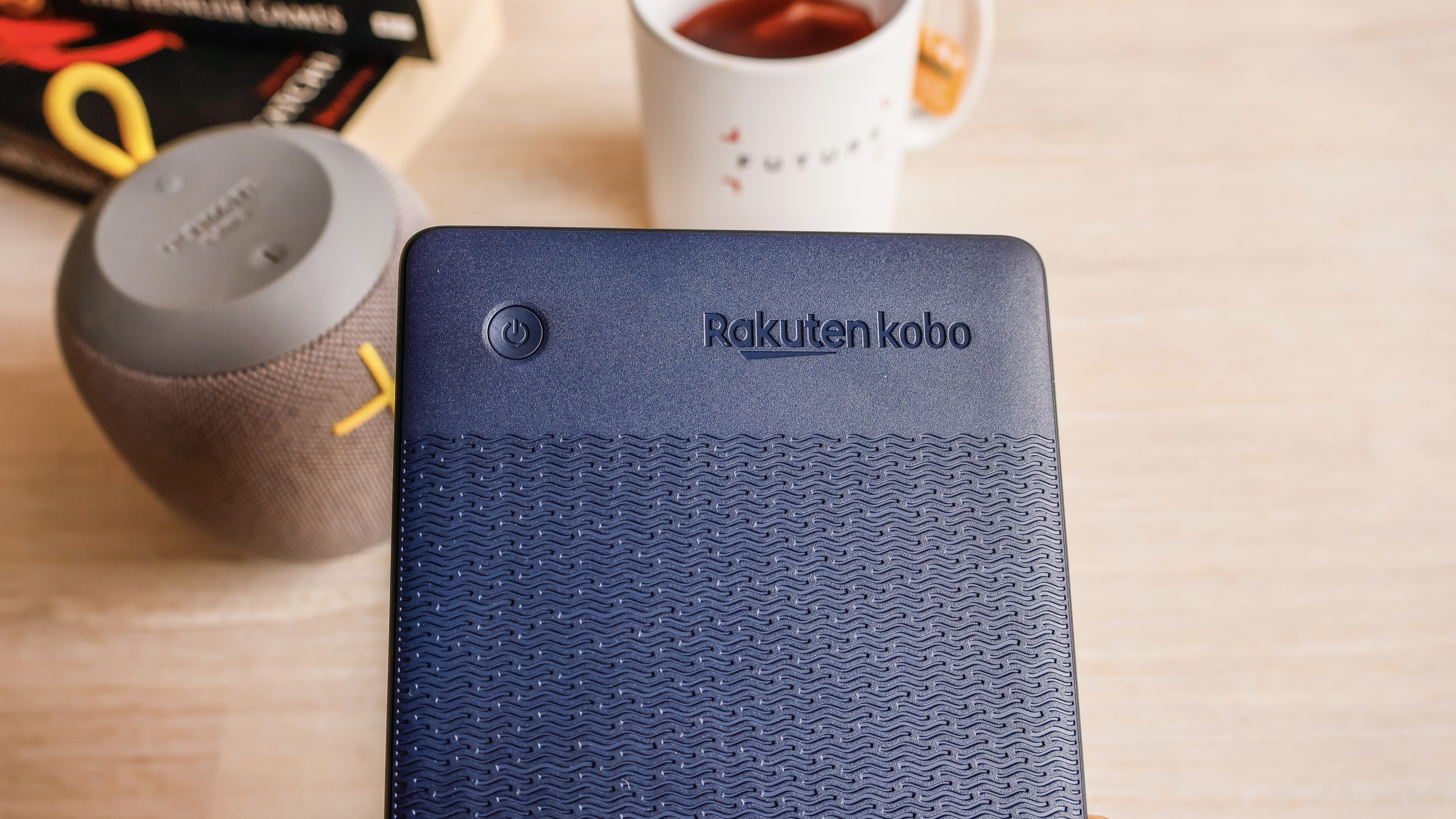 An up close shot of the Kobo Clara 2E's back panel showing the logo and texture imbedded in navy blue plastic.