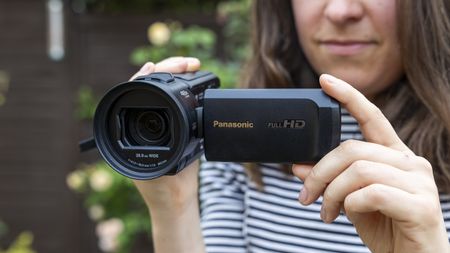 A female holding the Panasonic HC-V900 in a garden