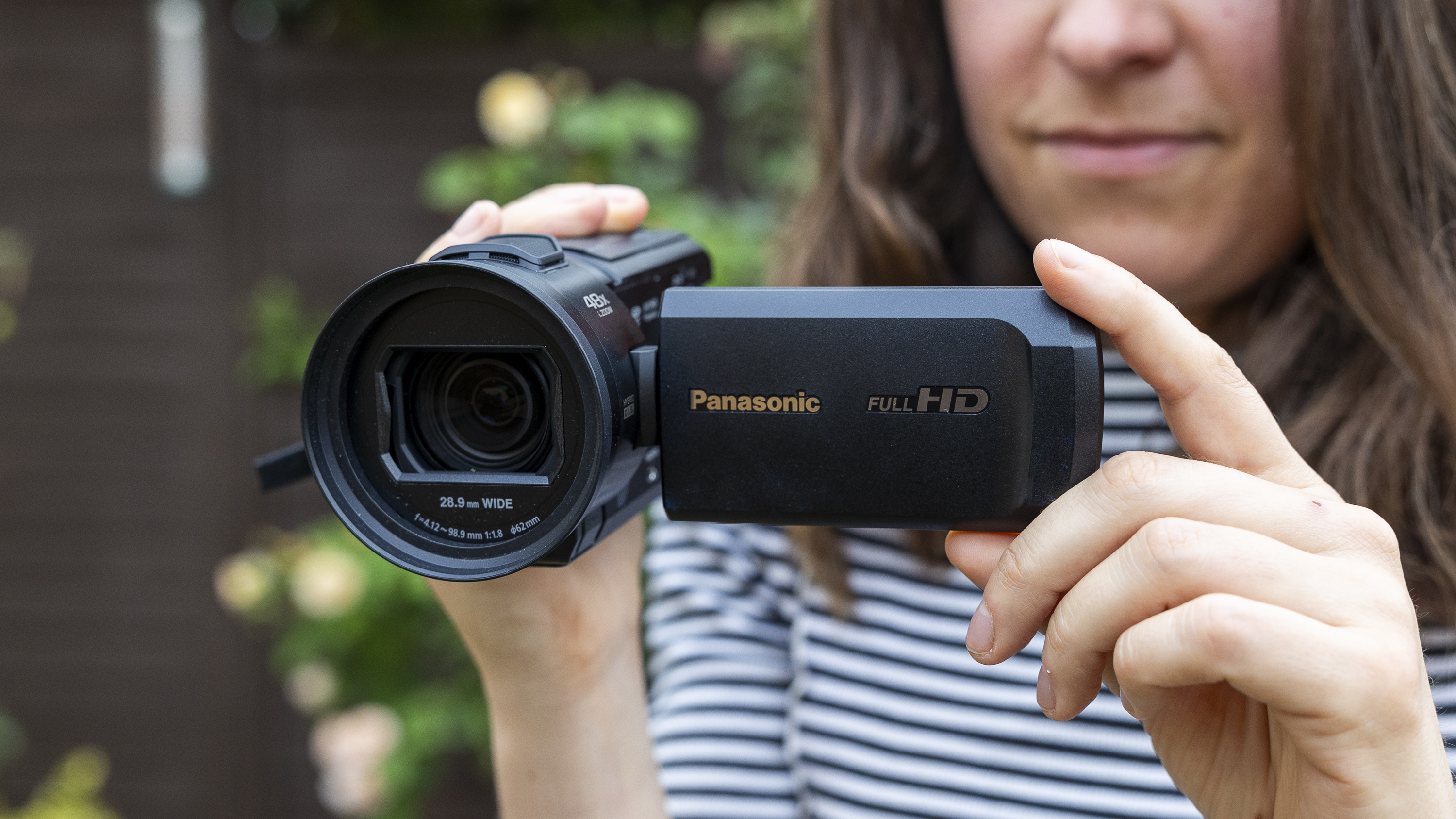 A female holding the Panasonic HC-V900 in a garden