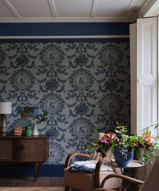 Blue repeat pattern wallpaper with white ceiling and window and armchairs