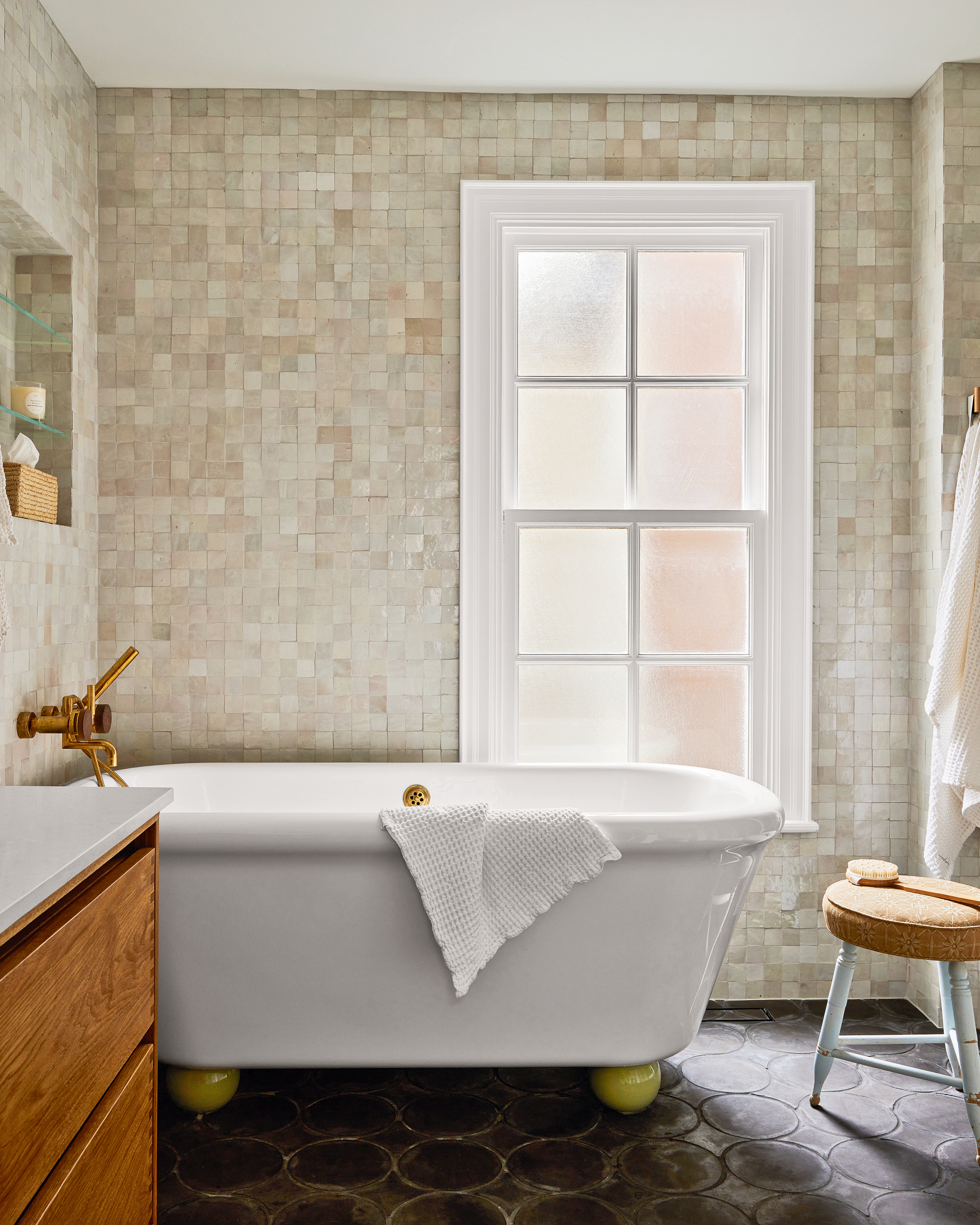 Bathroom with beige zellige wall tiles, brown floor tiles, white bathtub with chartreuse ball feet