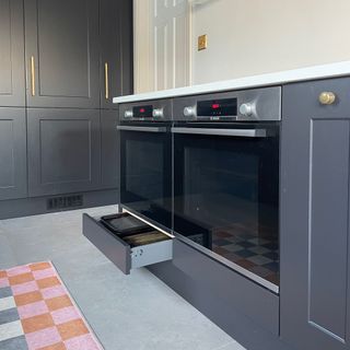 Two single ovens in a run of grey base units with narrow drawers underneath