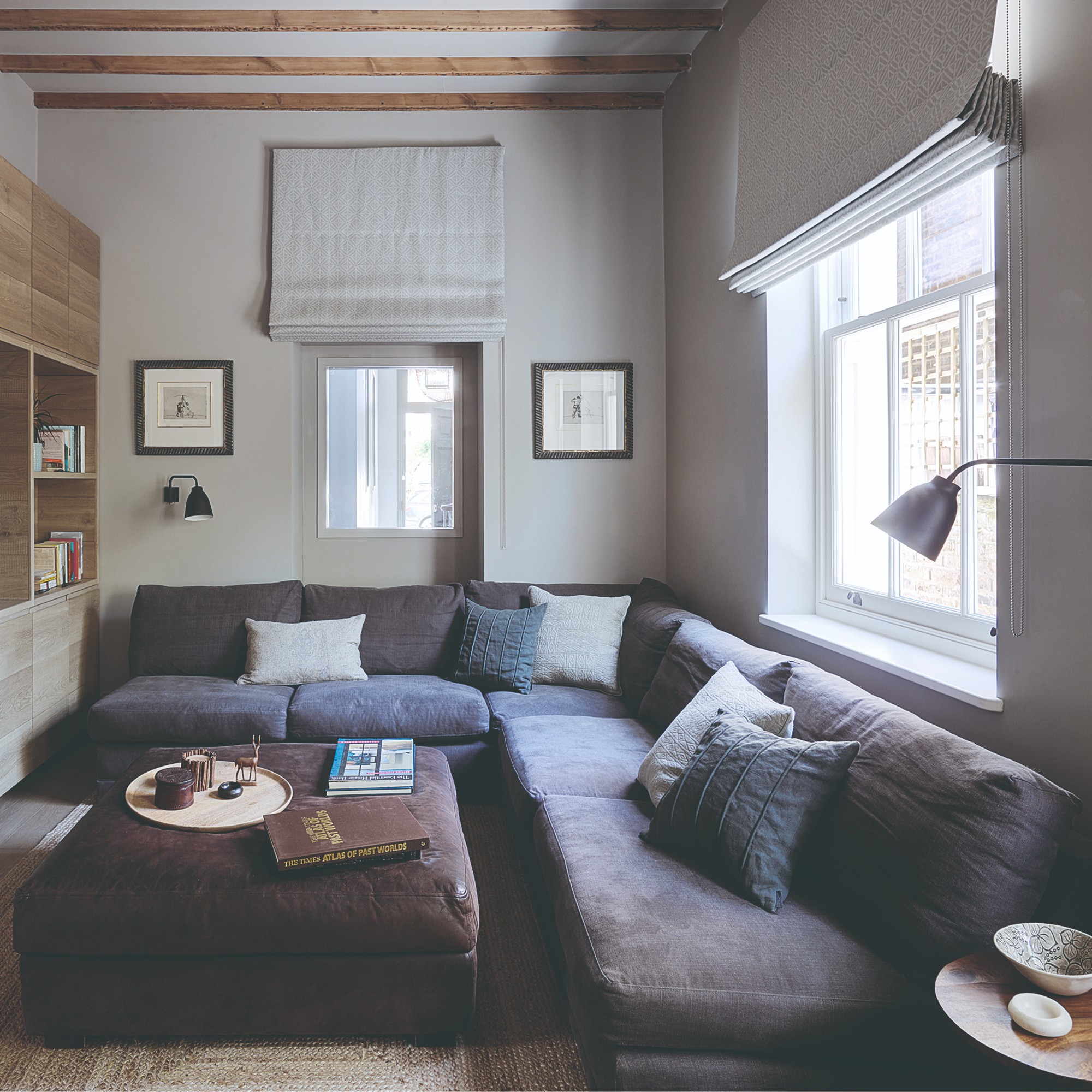 A cinema room with a deep-seated corner sofa and an ottoman used instead of a coffee table
