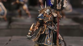 A new Stormcast Eternals model with a skull helmet stares out into the foreground while holding a hammer and staff