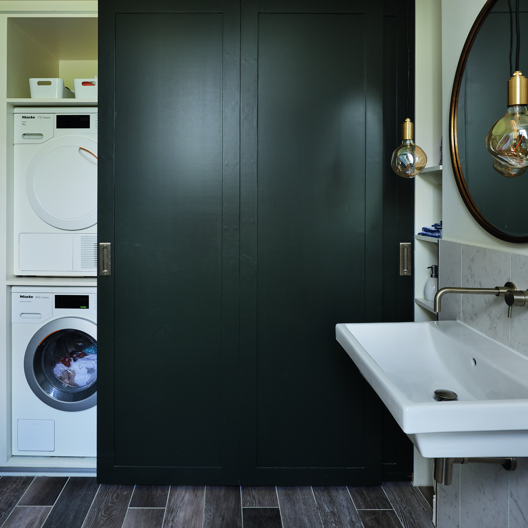 Utility room with stacked appliances behind navy sliding door