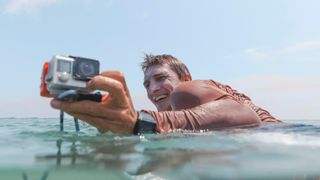 Man on surfboard holding GoPro camera