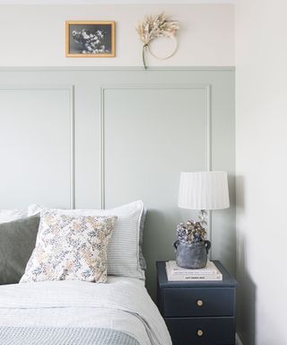 bedroom with pale blue painted panelling behind double bed made with striped bedding