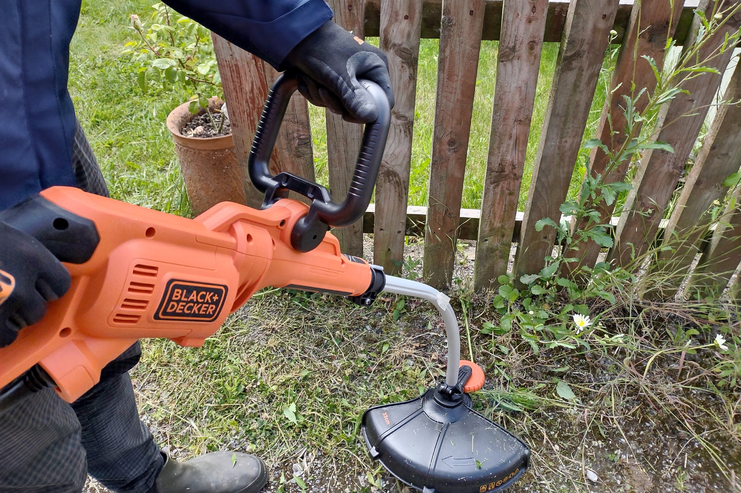 man holding the black + decker gh3000 and strimming weeds