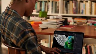 Woman using MacBook Pro in library