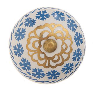 A white ceramic door knob with ornate blue and gold floral design