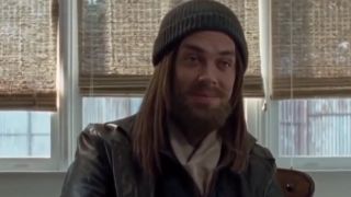 Tom Payne with a beard, smiling, wearing a knit cap