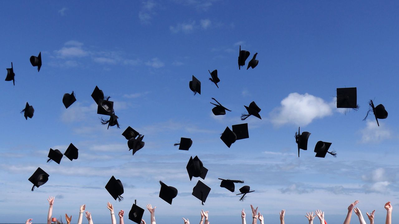 Students throw their graduation caps into the air