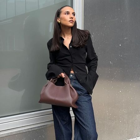 @ingridedvinsen wearing dark-blue pintuck jeans with a black fitted button-down shirt and dark brown leather tote