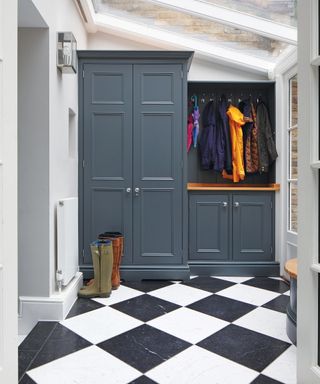 A mudroom with checkered floors and a blue closed cabinetry unit