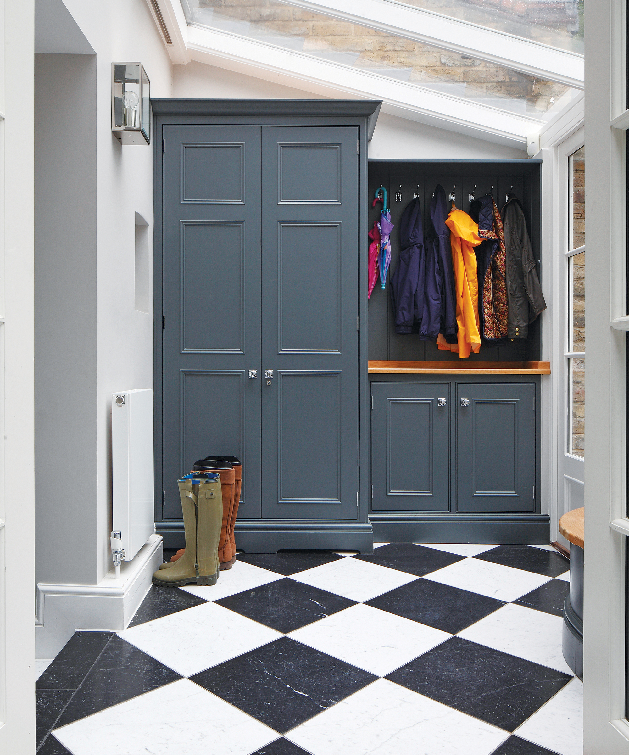 A mudroom with checkered floors and a blue closed cabinetry unit