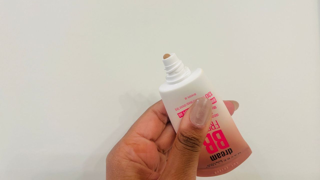 A person holding an opened Maybelline Dream Fresh BB Cream for the best foundations with SPF.