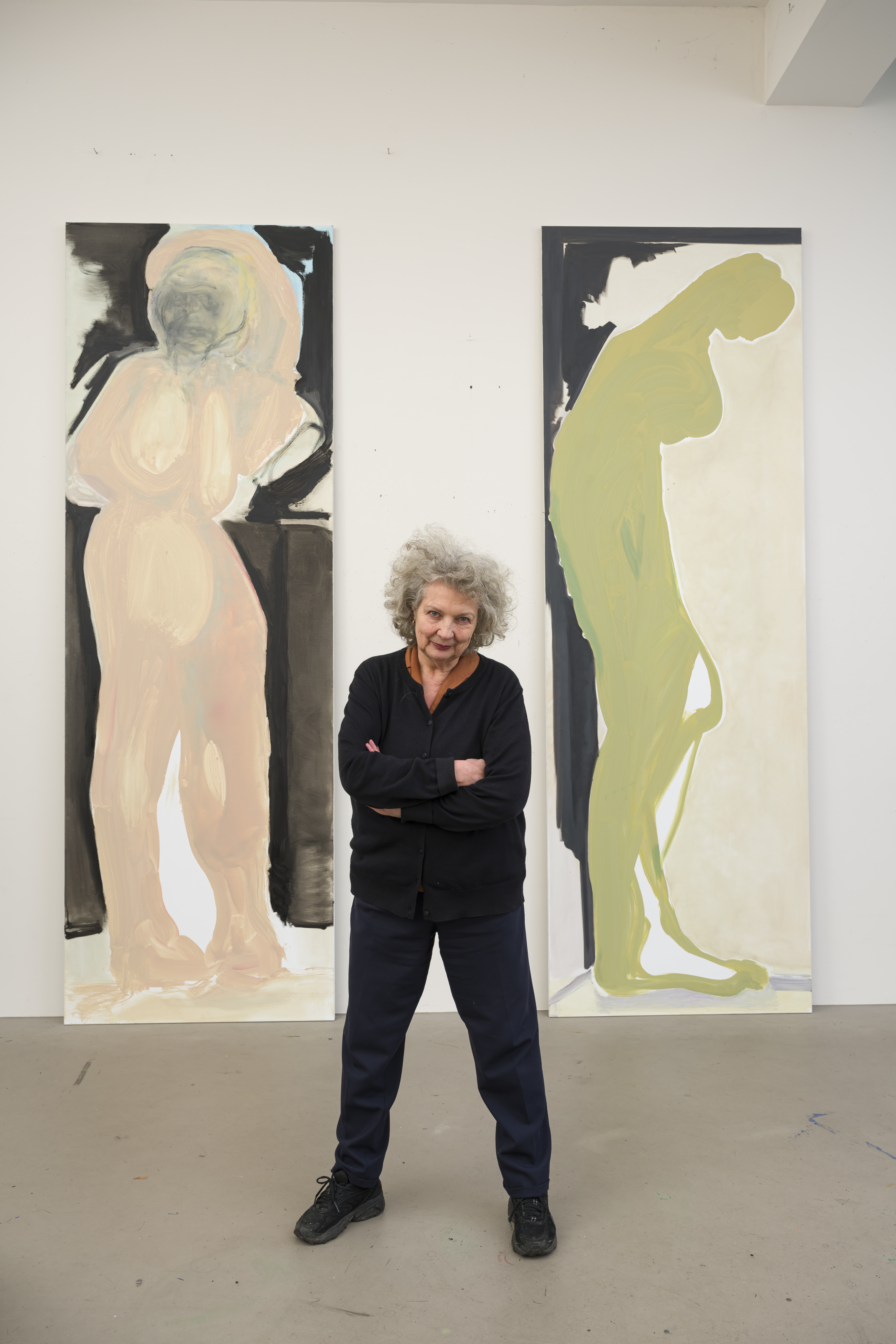 Artist Marlene Dumas standing in front of two large paintings