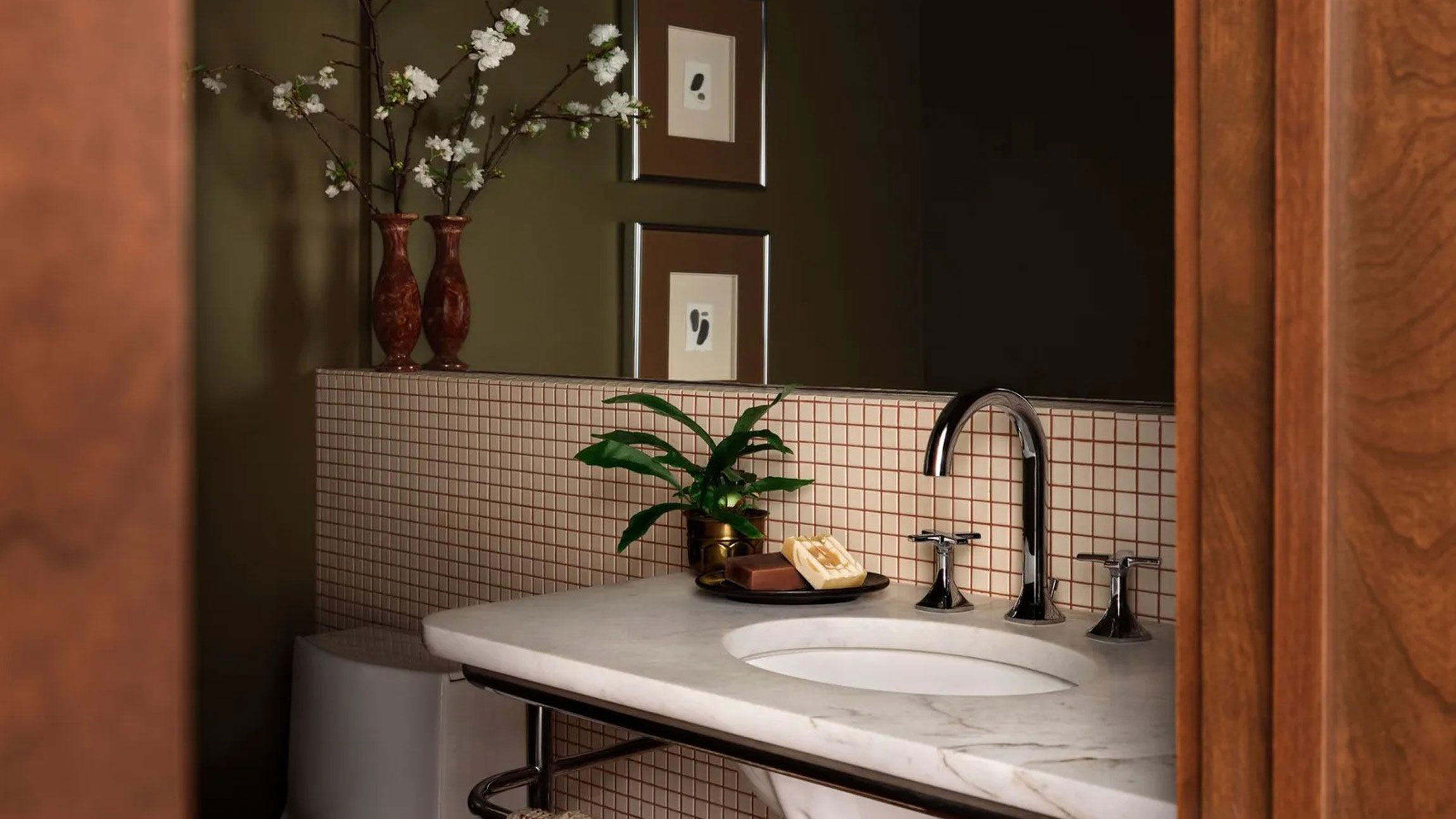 A green bathroom with checkered backsplash and a dark wooden door, designed by Joanna Gaines