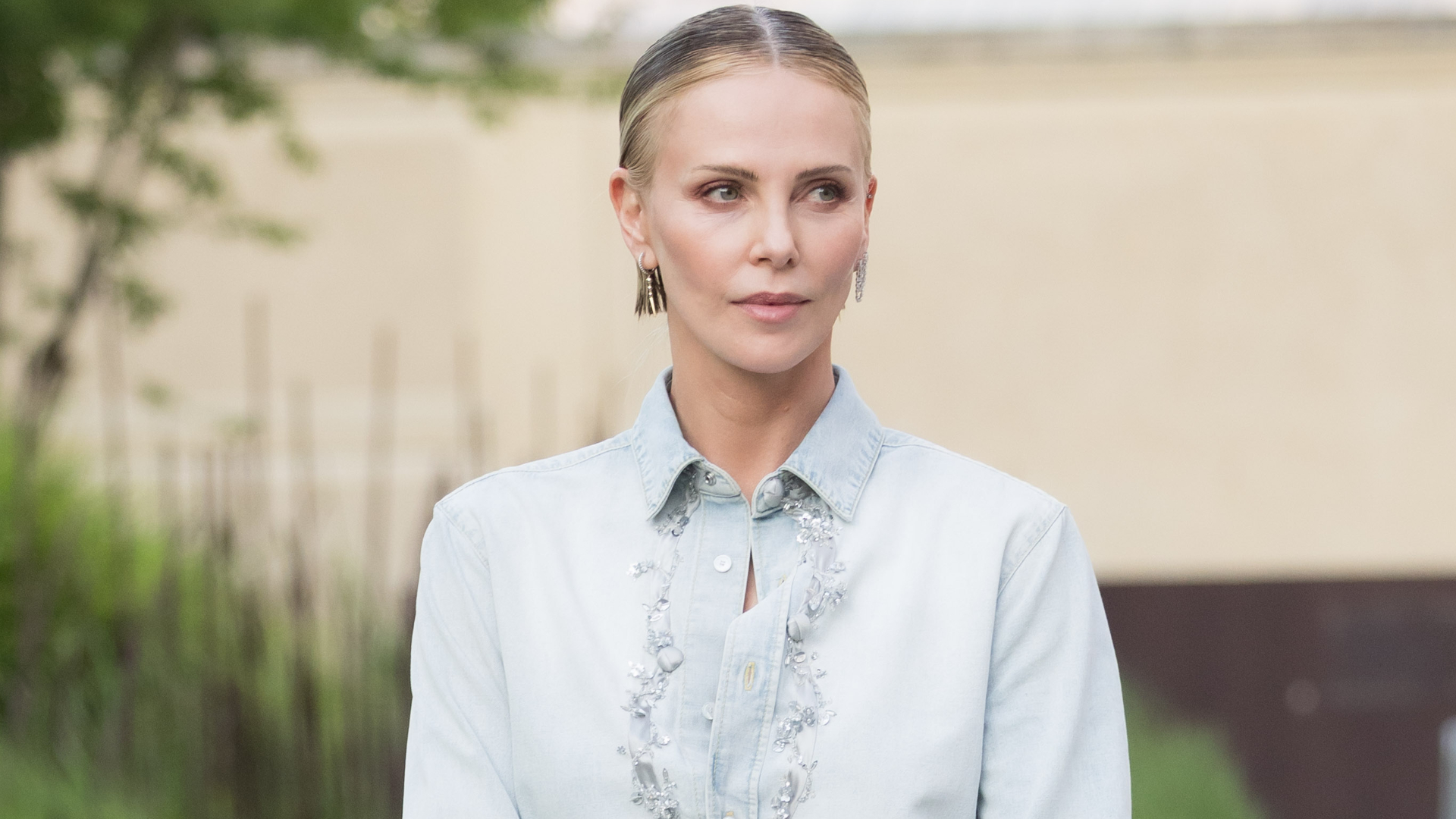 Charlize Theron styled surprising ankle boots from Dior with a denim button-down and black mini skirt