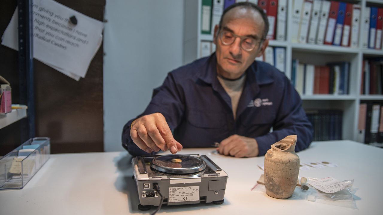 Robert Kool, a coin expert at the IAA, weighs one of the gold coins found in the Jewish Quarter of Jerusalem.