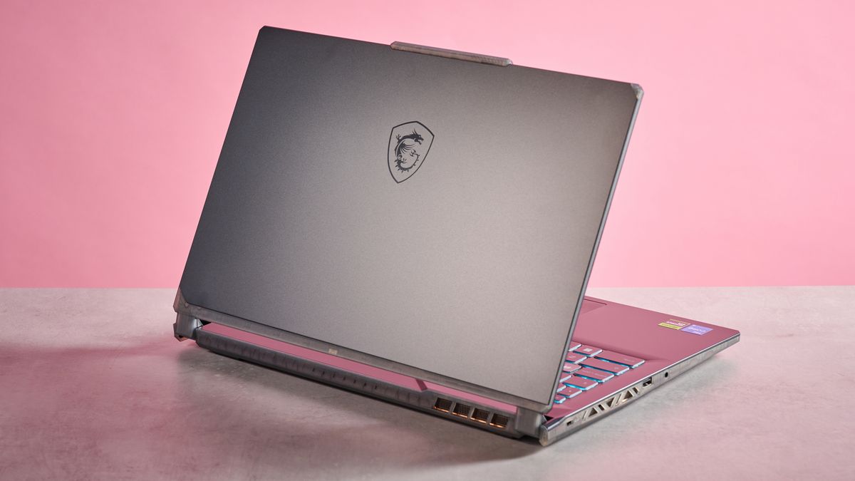 Rear three-quarter view of MSI Cyborg 15 A13U open on desk on a pink background
