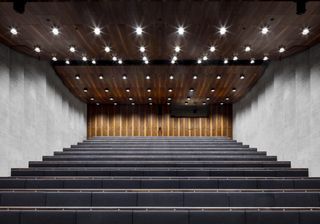 Looking up from bottom to top in a 13 row auditorium with with black seats.