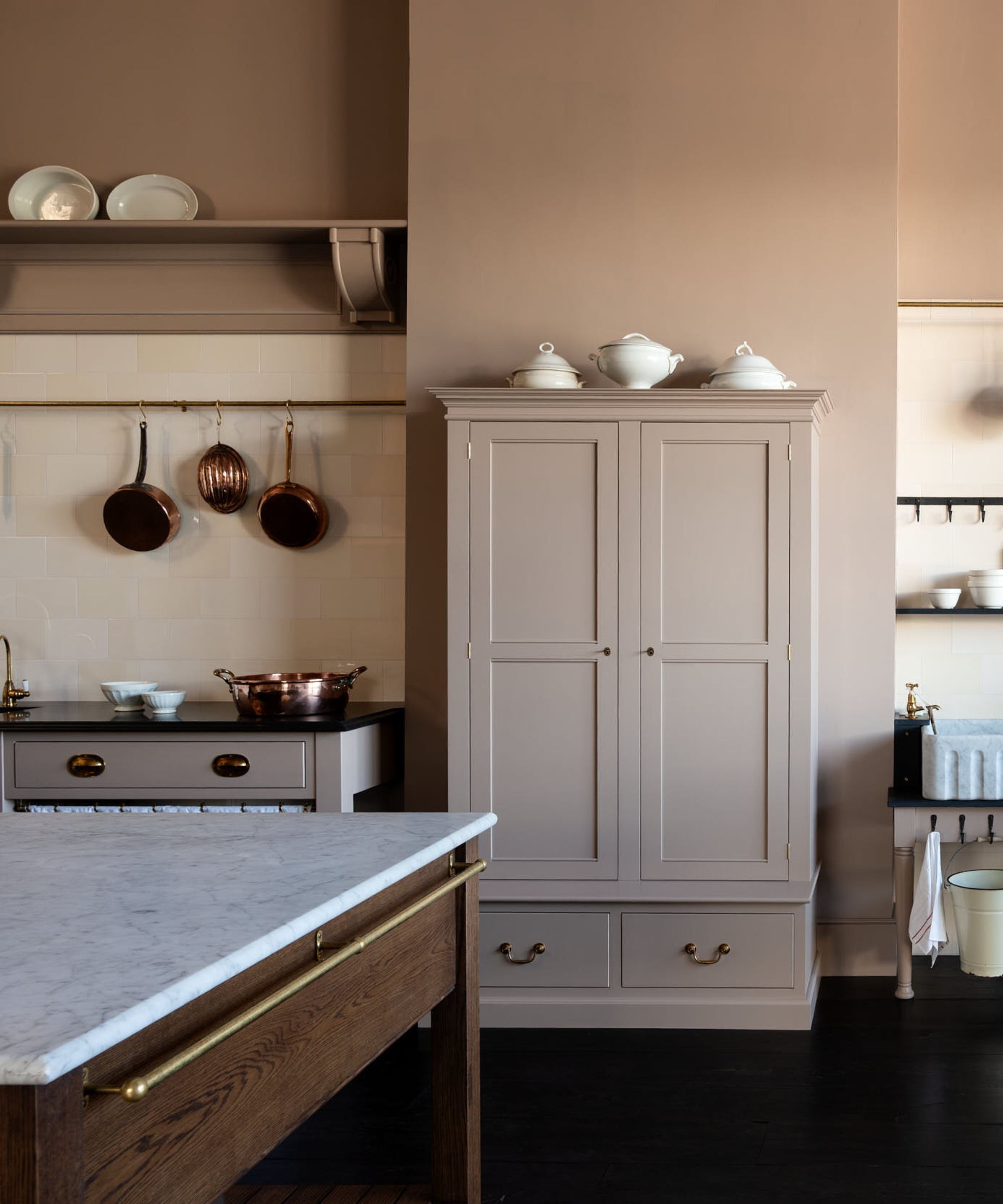 A light pink kitchen with a freestanding pantry cupboard painted the same color as the walls