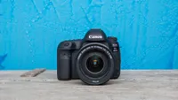 The Canon EOS 5D Mark IV sitting on a stone floor in front of a blue wall