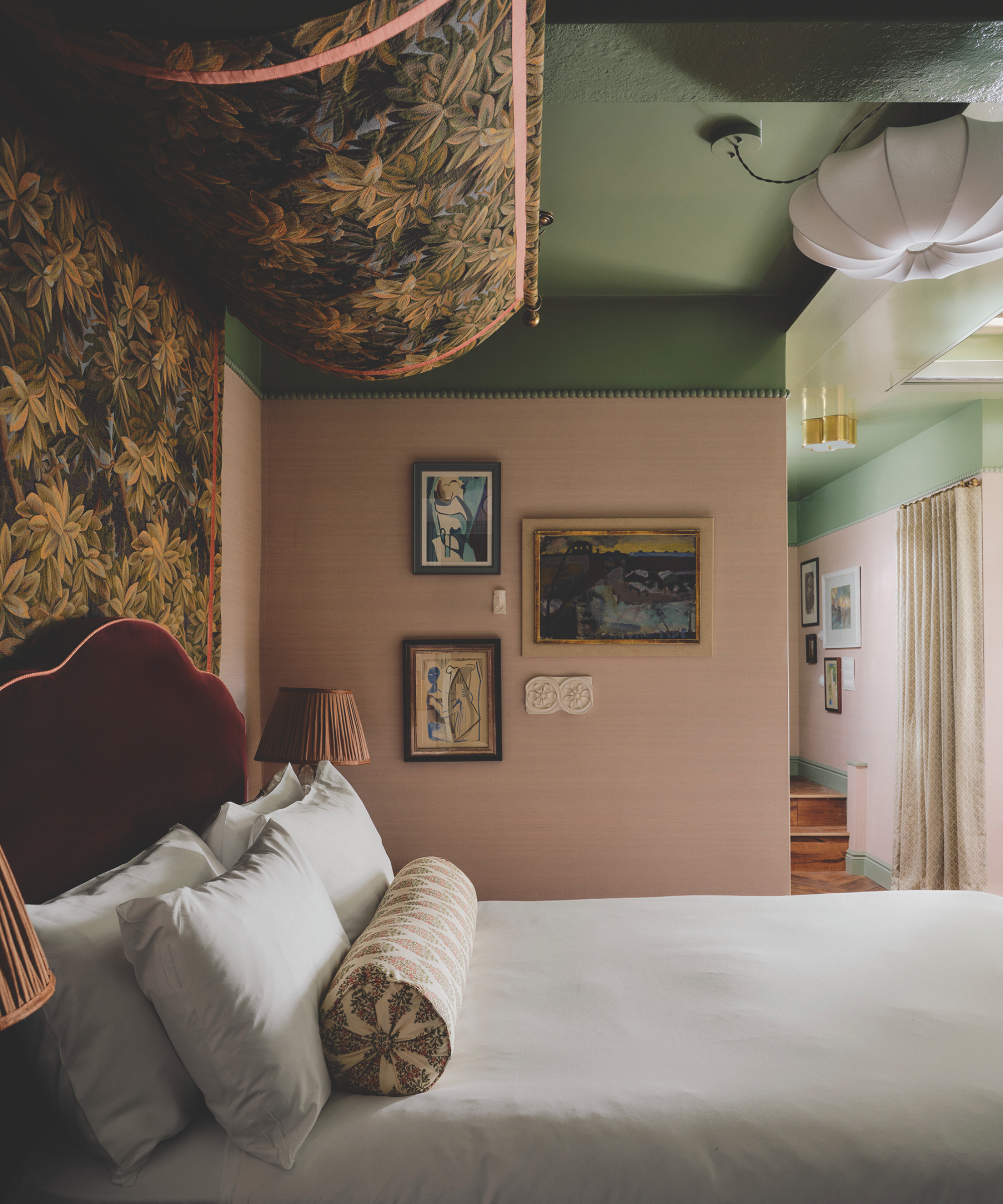 A pink bedroom with a green ceiling and a fabric canopy four poster.