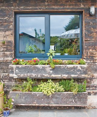 Window boxes on rustic wood cladding illustrating small vegetable garden ideas.