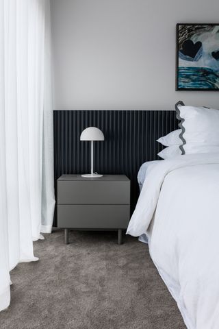 A bedroom with a gray headboard and white bedding