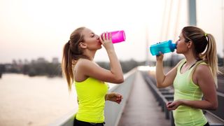 two women drinking from sports bottles