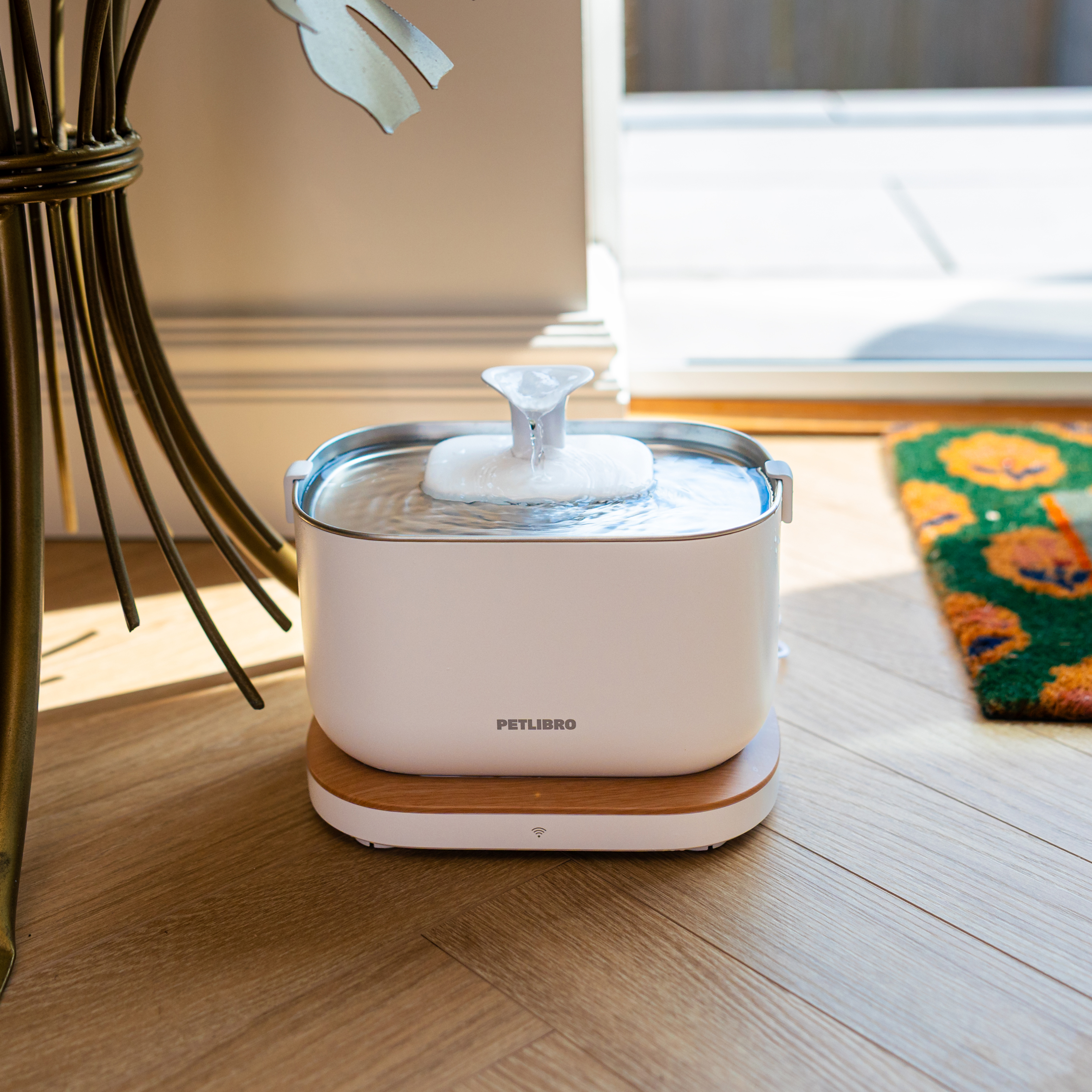 White smart pet bowl on a light wood herringbone floor