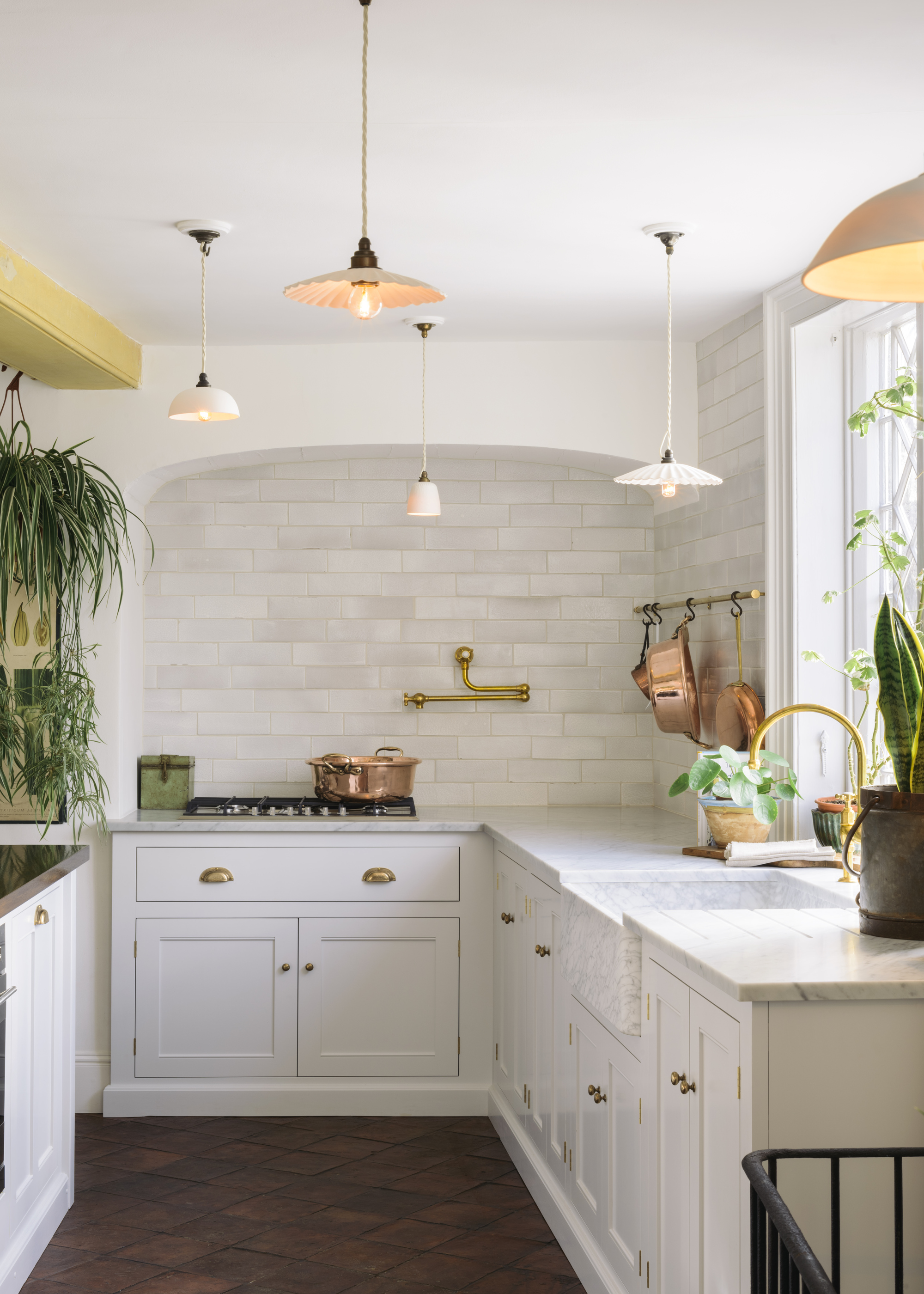 A kitchen with white inset shaker cabinetry, zellige wall tiles, and a range oven in an alcove nook