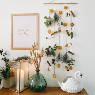 Natural Christmas wall hanging on white wall with a green vase, lantern and swan vase