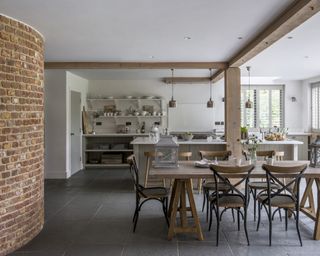 A large farmhouse kitchen with slate floor tiles and exposed brick wall.