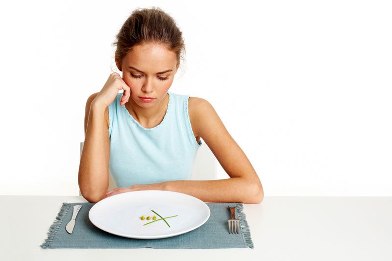 A woman staring at an almost empty plate.